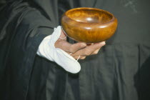 Cropped view of Zen Buddhist monk holding bowl for collection of alms.
