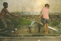 Two young boys drawing water from rowerpump.General File Water