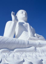 Angled view of large white seated Buddha seen from below looking up.