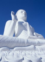 Angled view of large white seated Buddha seen from below looking up.