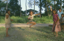 Young girls with skipping rope playing beside road.