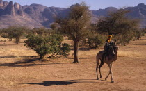 Touareg man on camel passing the Dyounde Mountains.