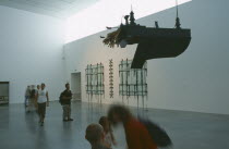 Tate Modern. Modern art exhibition room with piano suspended from the ceiling and visitorsArt Galleries
