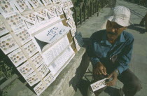 Local street vendor selling lottery tickets on the side of a path.