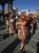 Street parade of men in traditional costume and head dress at Inti Raymi.