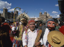 Group of musicians and masked dancers in traditional costume at Inti Raymi.  Three quarter view  facing the camera.