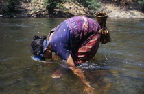 Mae Lui Village. Karen refugee woman gathering shellfish by hand using a snorkel to look at the riverbed