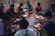 Mae Lui Village. Group of Karen refugees in a circle butchering a pig