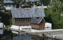 Minankabu house with people washing clothes in the lake outside