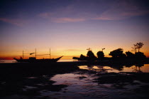 Boat and rocky outcrop silhouetted at sunset