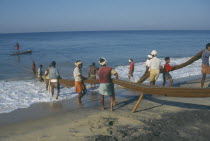 Fisherman landing fish on beach.