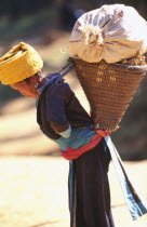 Hilltribe village woman carrying loaded basket on her back