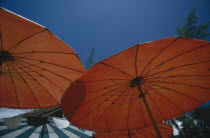 Open red sun umbrellas seen from below against blue sky
