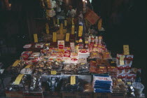 Ueno. Display of goods spilling out on to the street from a shop under an archway with the vendor standing inside