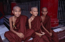 Three young monks sitting on the floor at the front of the temple Shwe Dagon Burma Rangoon