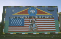 Red Indian mural depicting traditional indian figure standing against the American flag  on Whiterock Road  BelfastNationalist Murals