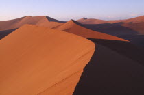 Red sand dunes partially cast in shadow