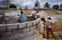 Men laying building blocks for a water tank in a small village with thatched huts