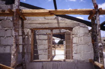 Building site with unfinished block built house and barred window.