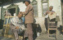 Men having their heads shaved by street barbers