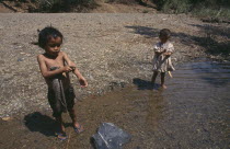 Two young Karen refugee children washing at the waters edge