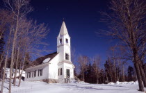 Saint Johns United Methodist Church  small white building with spire and steps leading to entrance  surrounded by snow with some on roof. winter winter