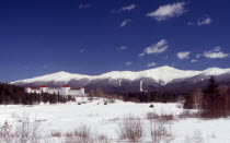 Mount Washington Hotel  large white building with red roof  snow peaked mountain range behind.  presidential rangewinter  presidential rangewinter