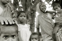 Extended family wait for social security benefits in a West Bengali village.  Black and white image.