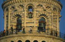 Campanile or Leaning Tower of Pisa.  Detail of top level and bells with visitors circling gallery.