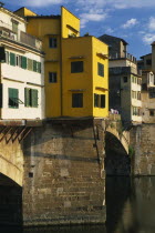 Ponte Vecchio.  Buildings on bridge above the River Arno with people sitting on wall.