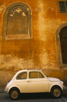 Italy, Tuscany, Florence, white Fiat 50 parked outside old building with faded ochre coloured plaster wall.