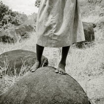 A young Indian female orphan stands on a rock in a cobra-infested piece of farmland.