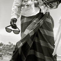 A sunglass-seller displays his wares on a tourist beach in southern India. Kerela Kovalum