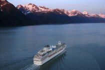 Cruise Ship with snow capped mountaind behind.