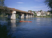Covered wooden bridge over the Rhine which links Badsackingen with the Stein in Switzerland. People in row boat.