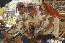 Portrait of young Paduang girls in costume  reading a magazine  long neck  metal rings.