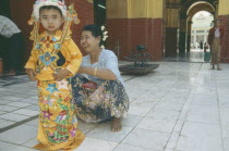 Young boy being dressed by woman for ordination ceremony Mahamuni Paya. Great sage Pagoda.Myanmar