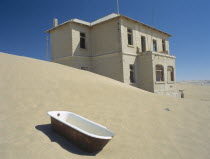 A house with a bath tub in the foreground  with desert sands encroaching. Ghost Town Diamond mining town near Luderitz abandoned since 1956