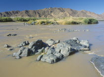 Rocks in the  water in The Orange River further west after being joined by the Fish River.