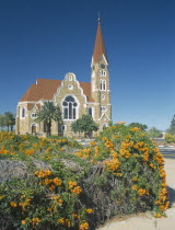 Christuskirche church exterior viewed from Parliament Gardens with a flowering bush in the foreground.