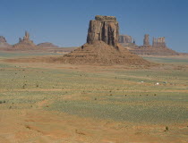 View across the valley towards rock formations and a Indian settlement on the desert ground below