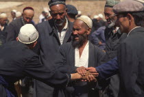 Tajik men touching hands striking a deal with central man acting as a witness