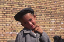 Portrait of young Tajik boy standing in front of brick wall