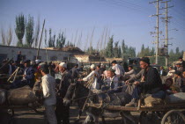 Busy street with crowds of men some traveling on donkey and cart
