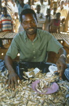 Portrait of male market stall holder selling dried fish. Able to do this due to micro credit loans.Man called Peter Makfero Hamilton