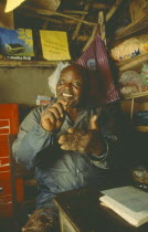 Chikondano Village. Disabled male shopkeeper sat in his small shop. Able to run shop due to a community loan.Mr Nemulaloan of about 12