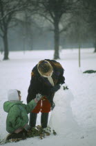 Woman and child building a snowman in heavy snow in Hyde Park.