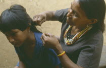 Macuna Indian woman checking her daughter s hair for lice.