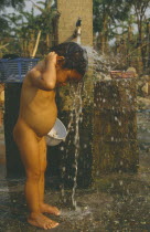 Young Hmong girl washing under stand pipe in Hmong returnee villages for ex-refugees from Thailand.