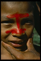 Portrait of Auca Indian with red achote paint decorating face.